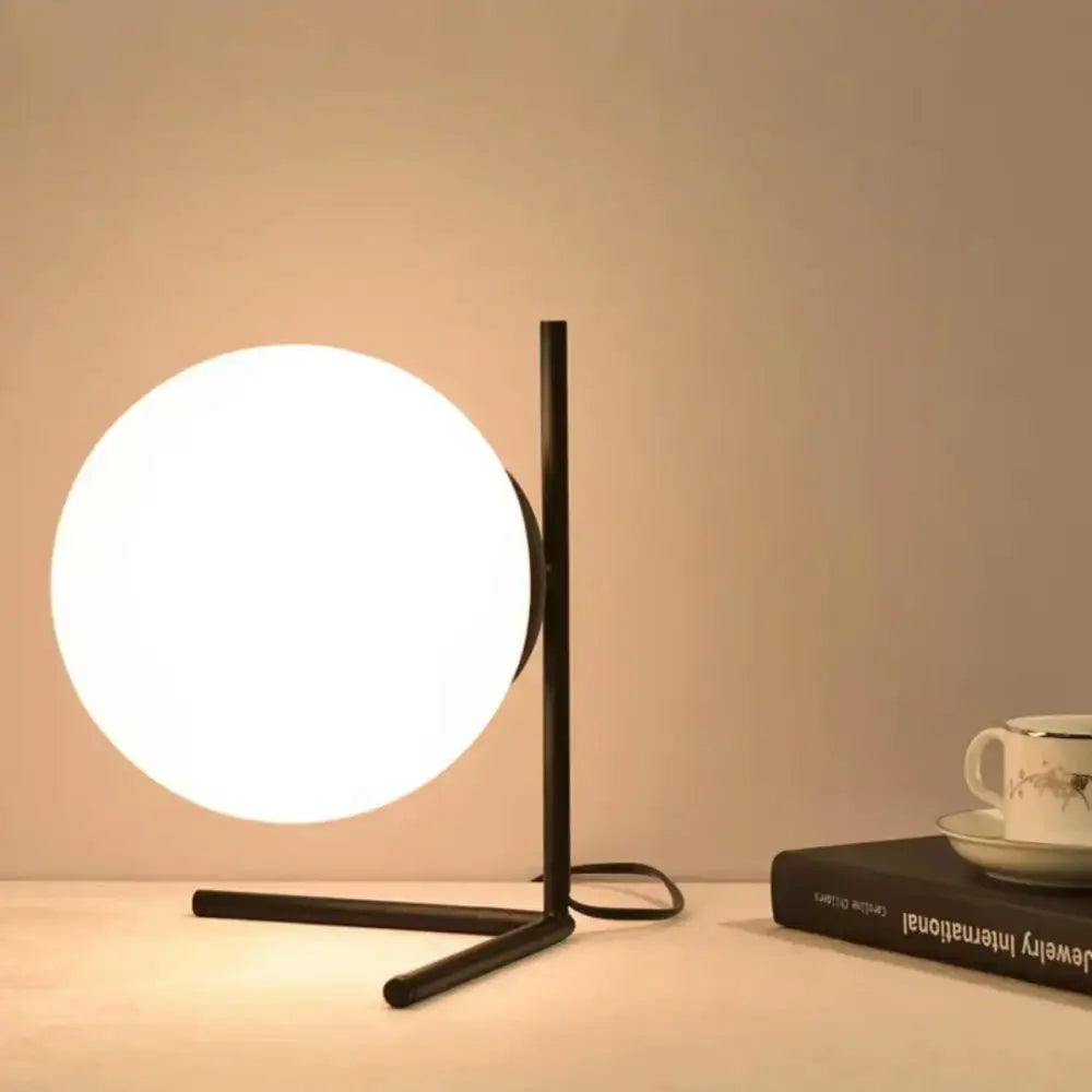 Black metal table lamp with a glowing white frosted glass ball shade modern decorbites glass ball table lamp