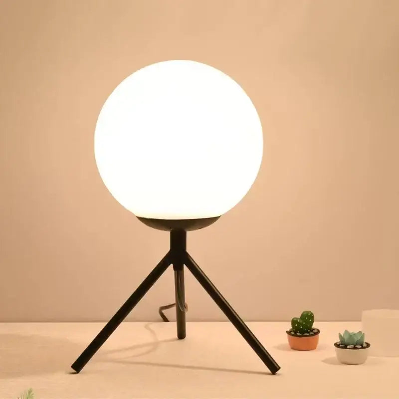 A sleek black glass ball table lamp with a glowing white spherical globe for modern bedroom decorbites decor