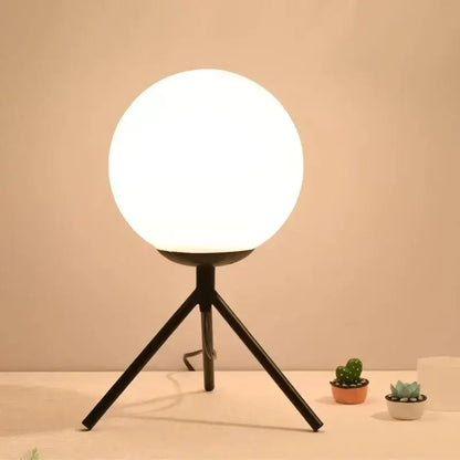 A sleek black glass ball table lamp with a glowing white spherical globe for modern bedroom decorbites decor