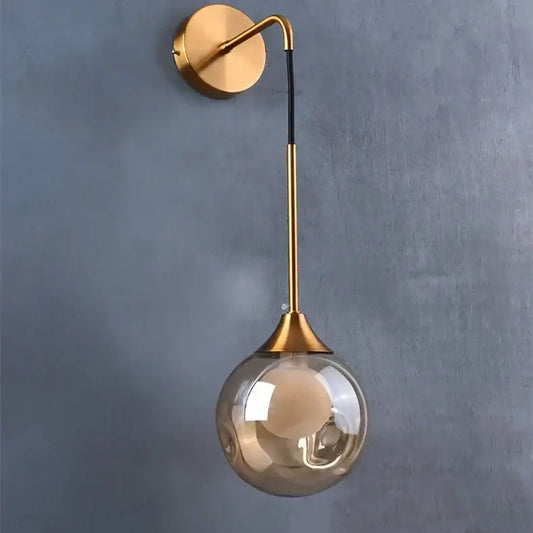 Modern gold glass ball wall lamp with curved arm and smoked glass shade for elegant bedroom decorbites glass ball sconce