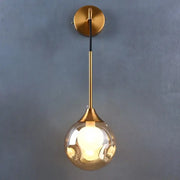 Modern gold wall sconce featuring a sleek glass ball teardrop lamp with an illuminated bulb by decorbites glass ball