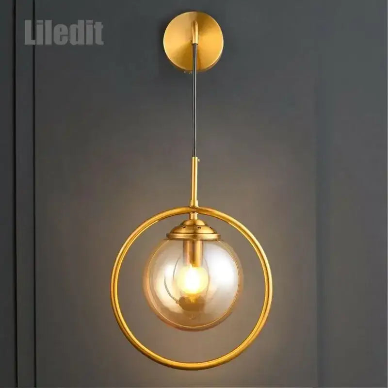 Modern gold glass ball wall sconce light fixture with a circular frame and clear glass globe by decorbites for bedroom decor