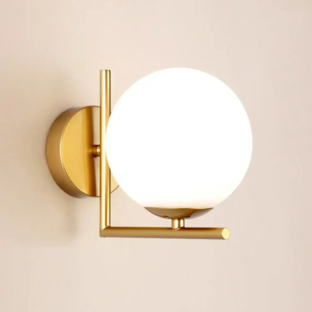 Modern gold glass globe wall lamp featuring a gold-toned metal frame and frosted glass globe by decorbites for bedroom decor