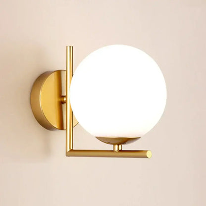 Modern gold glass globe wall lamp featuring a gold-toned metal frame and frosted glass globe by decorbites for bedroom decor
