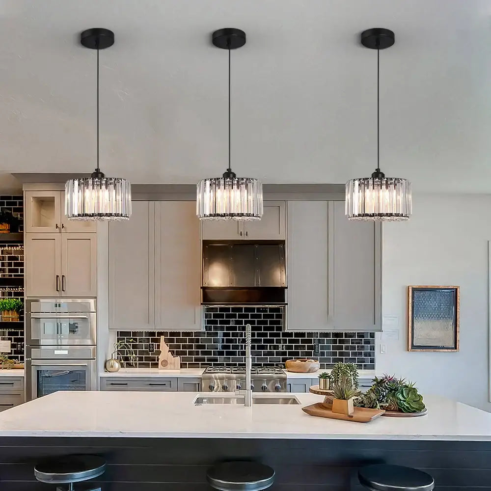 Three black pendant lights with clear crystal shades in a modern gold glass led chandelier ceiling light for dining room