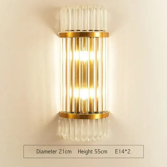 Modern gold wall sconce with vertical glass rod crystal design and warm glowing light for bedroom use