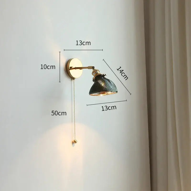 Modern gold wall light with adjustable arm featuring a vintage brass finish and dark green ribbed glass shade for bedroom use
