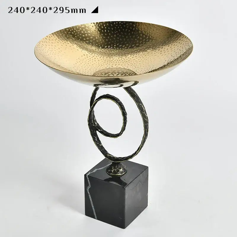 Modern gold hammered fruit bowl tray with twisted black metal stand and dark marble base for elegant dining room display