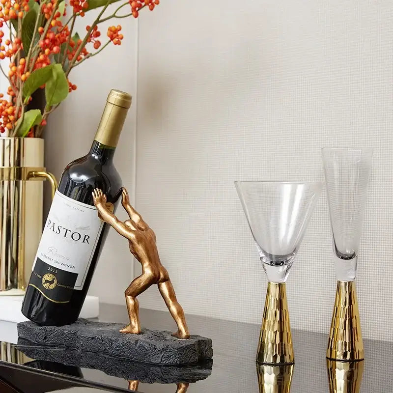Modern gold hercules figurines wine rack featuring a muscular man pushing a dark wine bottle on a textured base