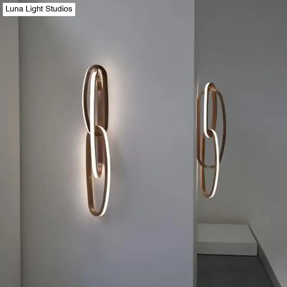 Modern copper-toned wall lamp with intertwined circular design and glowing led light strip for living room use