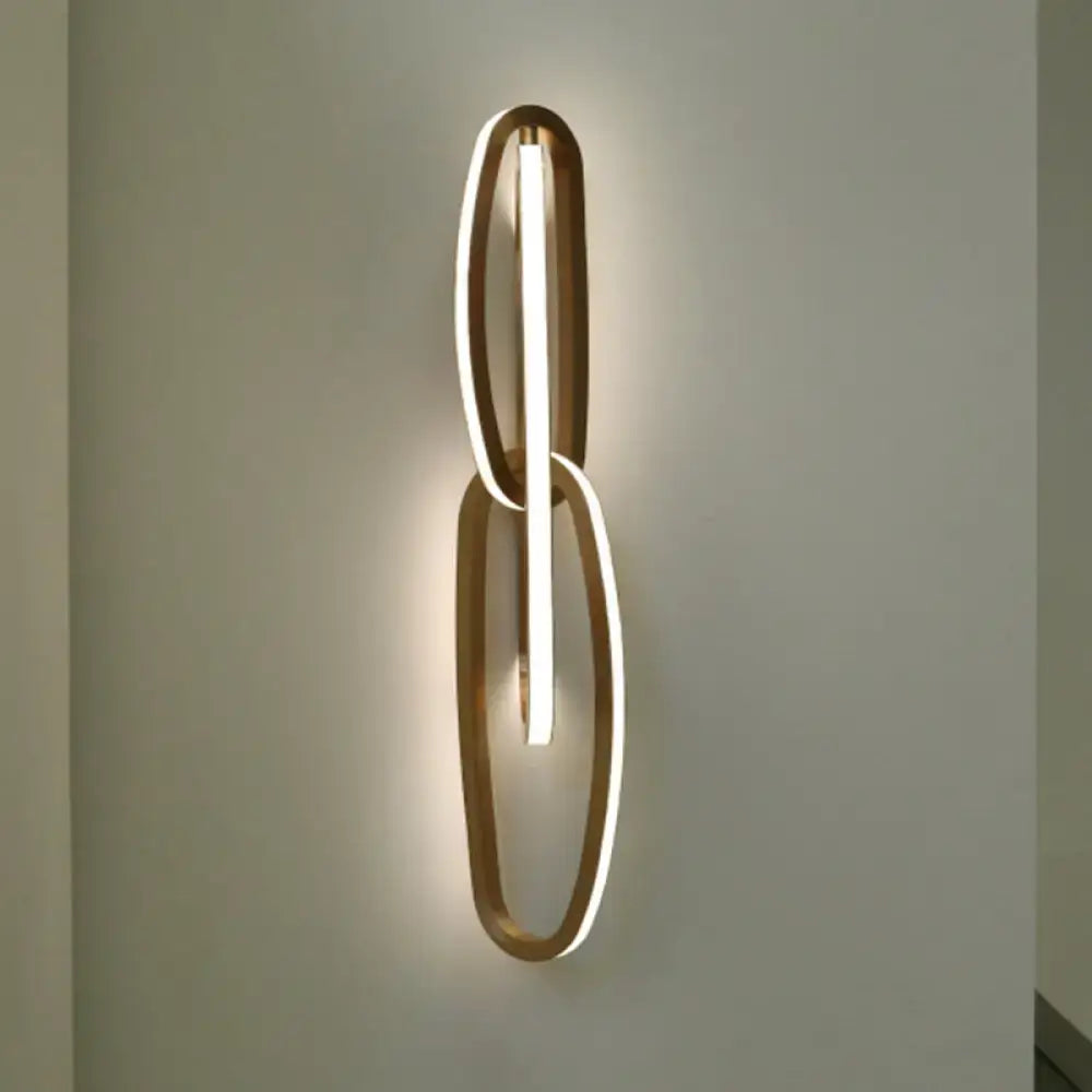 Modern gold wall lamp with two interlocking oval frames and central illuminated led strip for living room use
