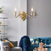 Modern gold iron candle wall light with two candle-style bulbs and clear glass shades for living room use