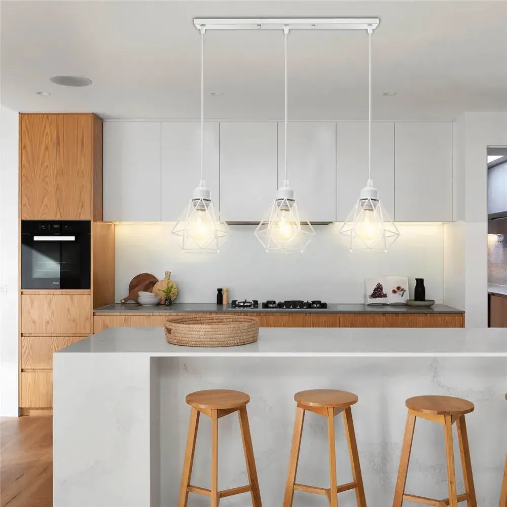 Three white geometric pendant lights with decorbites iron frame hang above a kitchen island as a frame pendant chandelier
