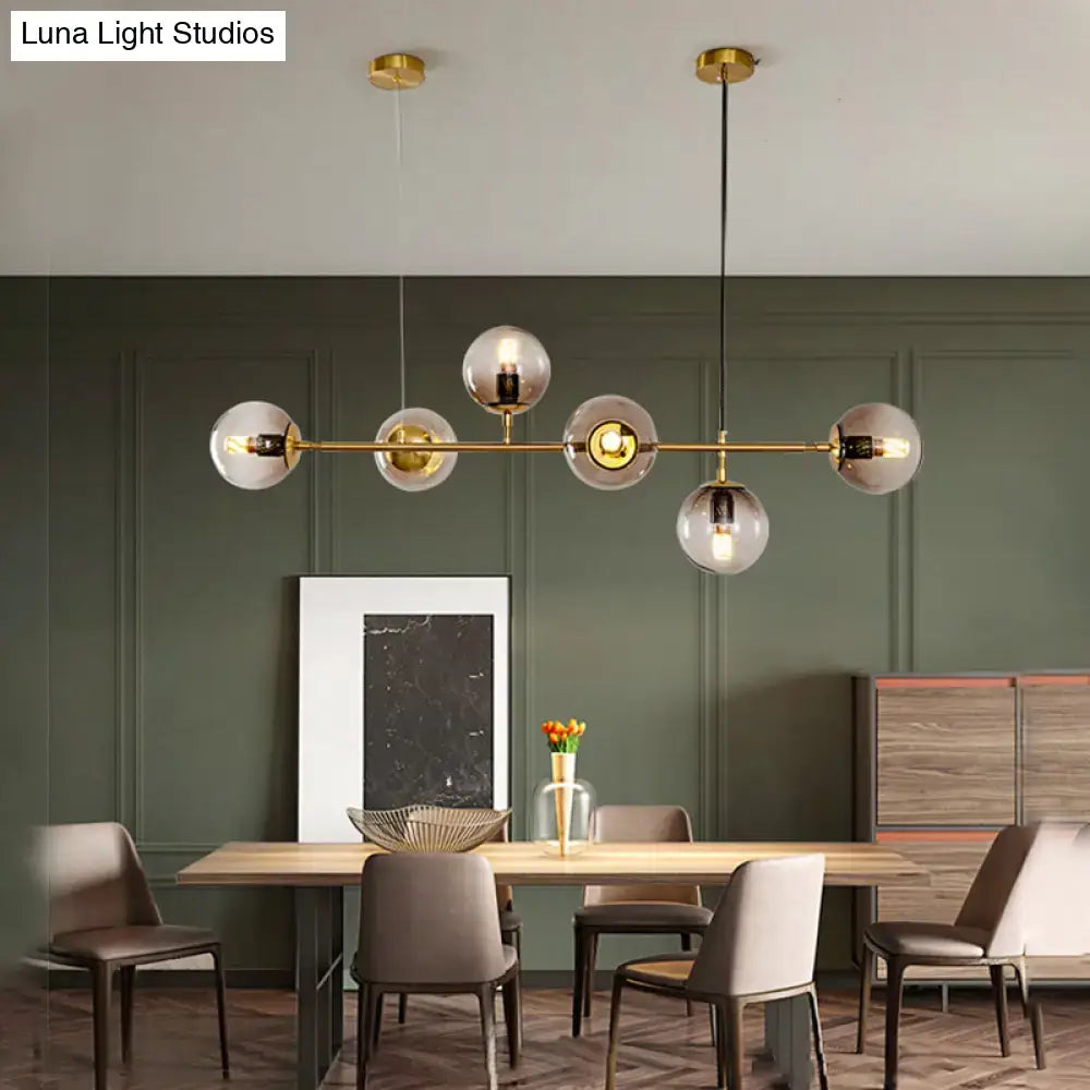 Modern gold island pendant light with clear glass globes and a sleek horizontal bar design for dining room use
