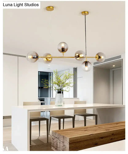 Modern gold island pendant light with spherical glass globes and brass bar for dining room illumination
