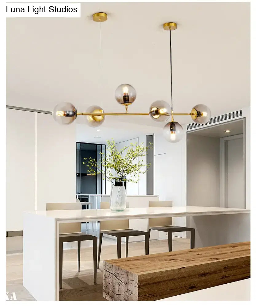 Modern gold island pendant light with spherical glass globes and brass bar for dining room illumination