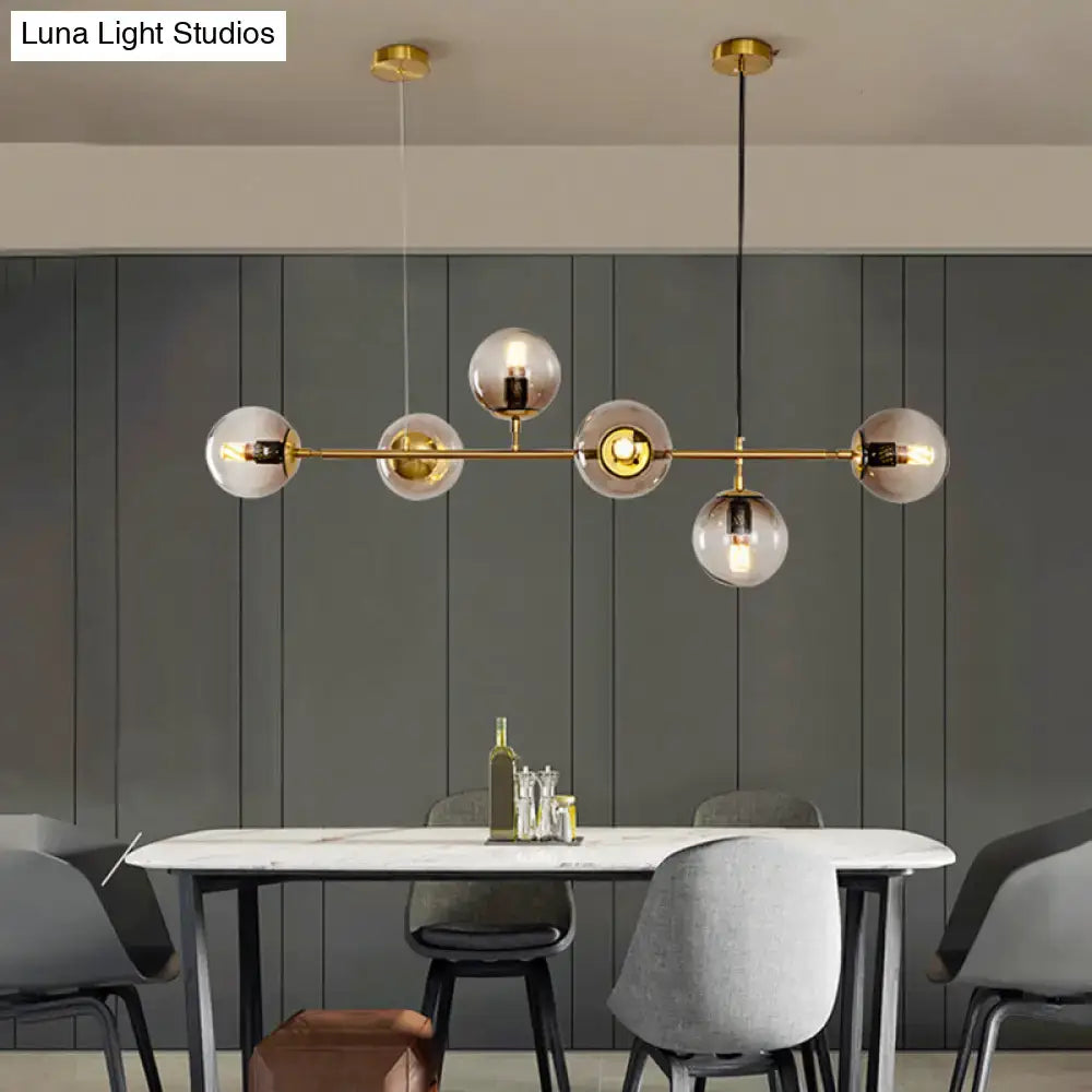 Modern gold island pendant light featuring five gold-toned spherical glass globes for dining room illumination