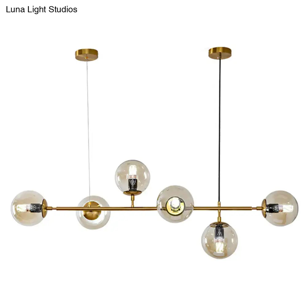 Modern gold island pendant light featuring gold-toned finish with clear glass globes and black-and-white cords for dining room