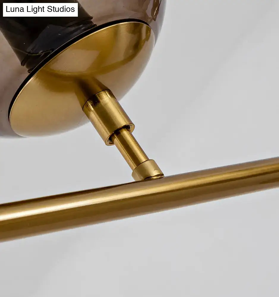 A sleek modern gold island pendant light with smoked glass globes and polished brass hardware for dining room