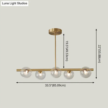 Modern gold island pendant lighting with brass finish and five clear glass globe shades for dining room island pendant lighting