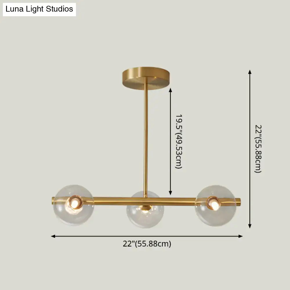 Brass-finished modern island pendant lighting with three clear glass globe shades for dining room illumination