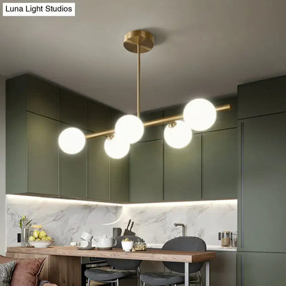 Modern brass island pendant lighting with five spherical glass globes for dining room illumination