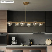 Modern gold island pendant lighting with five clear glass globe shades in brass for dining room pendant lighting