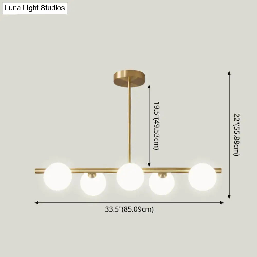 Modern gold island pendant lighting with brass finish and five frosted glass globe bulbs for dining room island pendant lighting