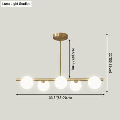 Modern gold island pendant lighting with brass finish and five frosted glass globe bulbs for dining room island pendant lighting
