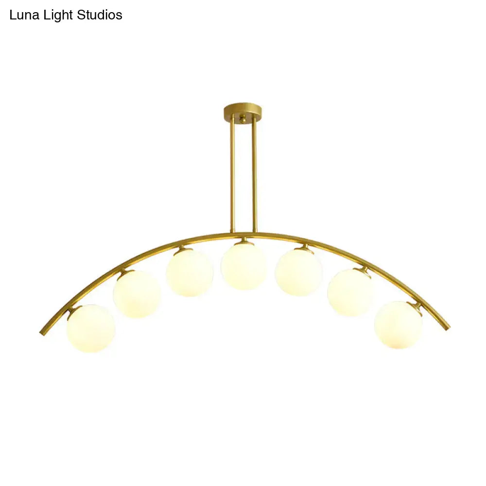 Gold-toned DecorBites island pendant with six frosted glass globe bulbs and clear white shade for modern kitchens