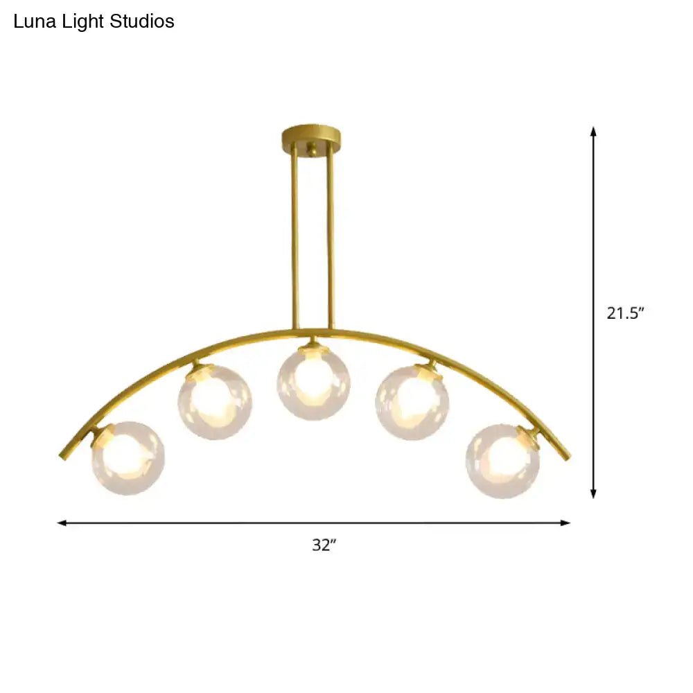 Gold-toned DecorBites island pendant with clear white shade featuring five spherical glass bulbs in a curvy design