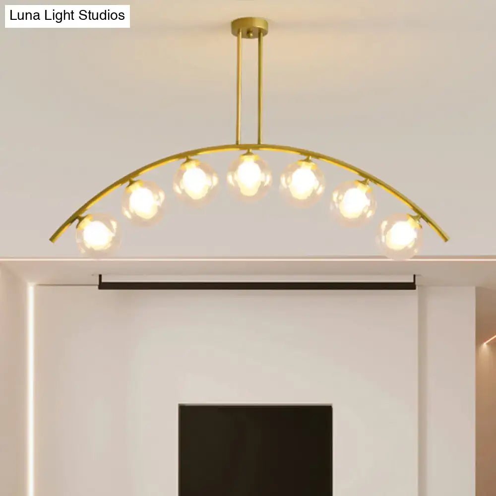Gold island pendant light with clear white shade featuring six clear glass globe bulbs and a curvy design