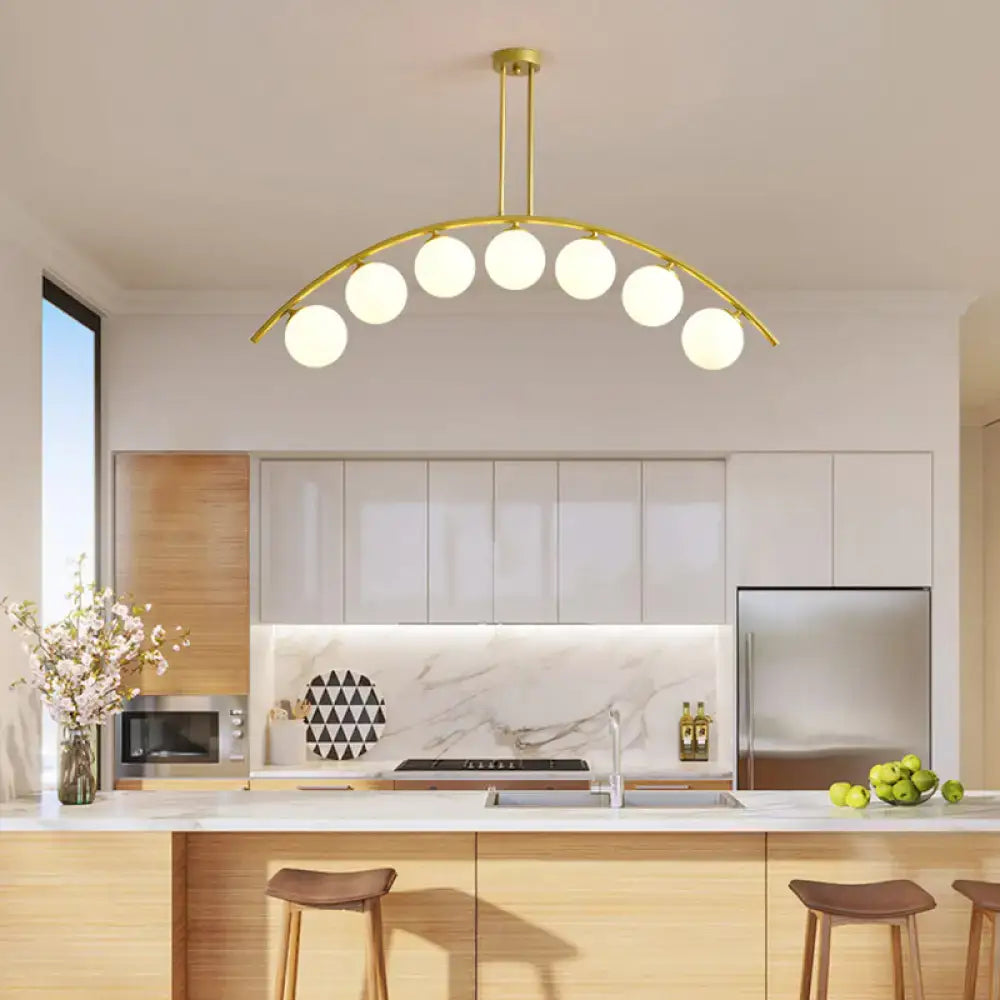 Gold-toned DecorBites island pendant with six spherical frosted bulbs and clear white shade for modern kitchens