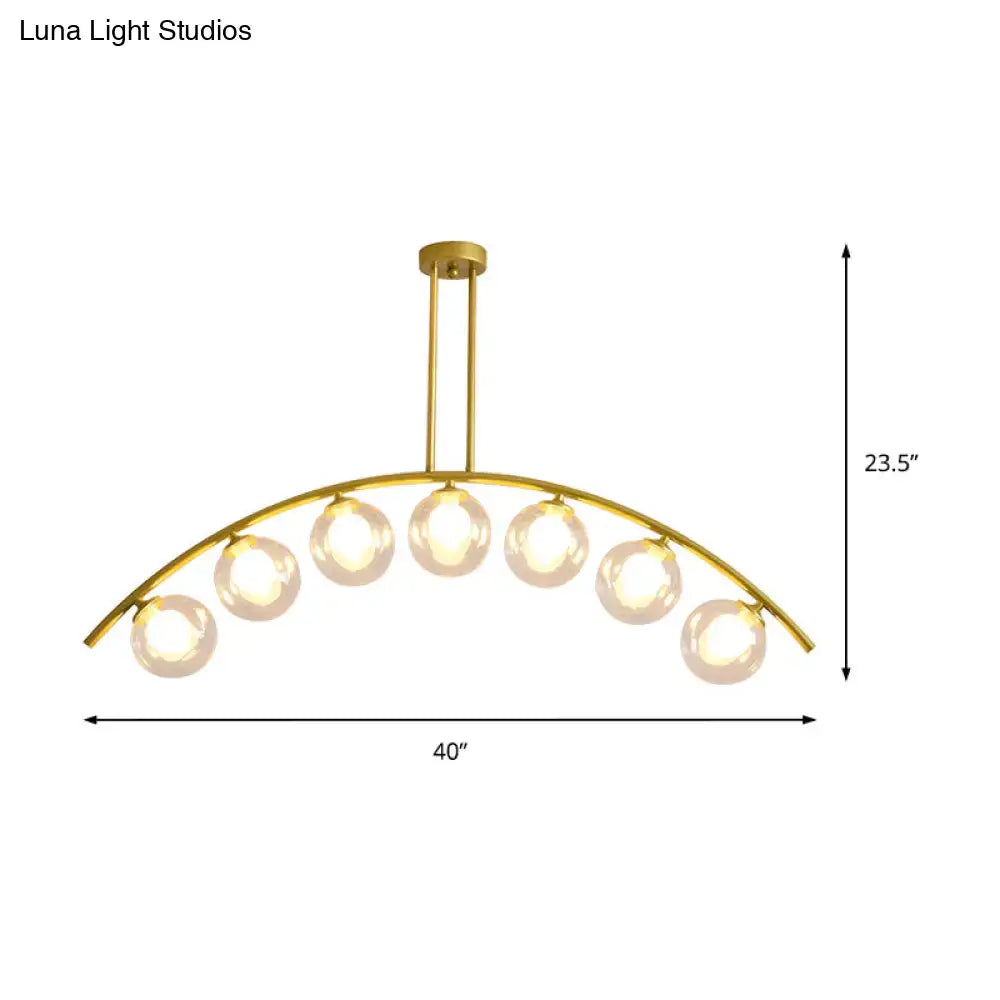 Gold-toned decorbites™ island pendant with clear white shade and six spherical glass bulbs for modern kitchens