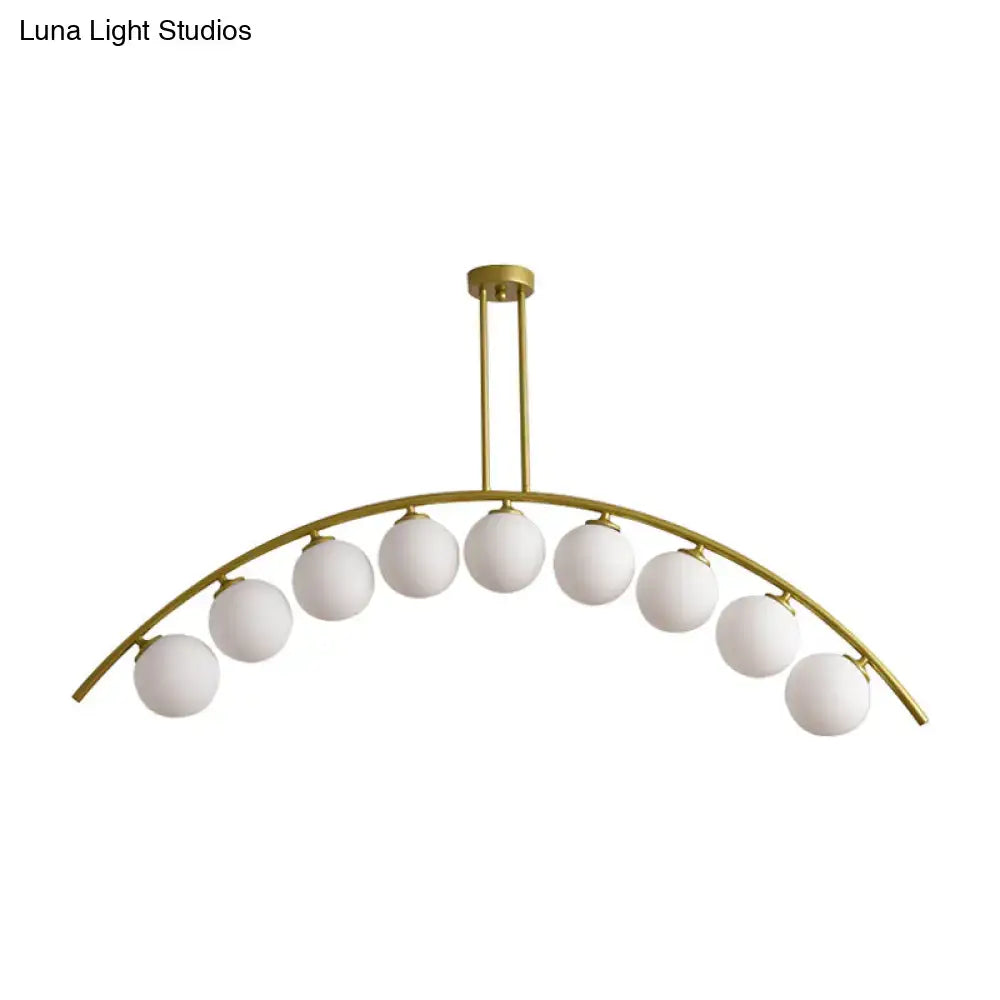 Gold-toned DecorBites island pendant with nine frosted globe lights and clear white shade for modern kitchens