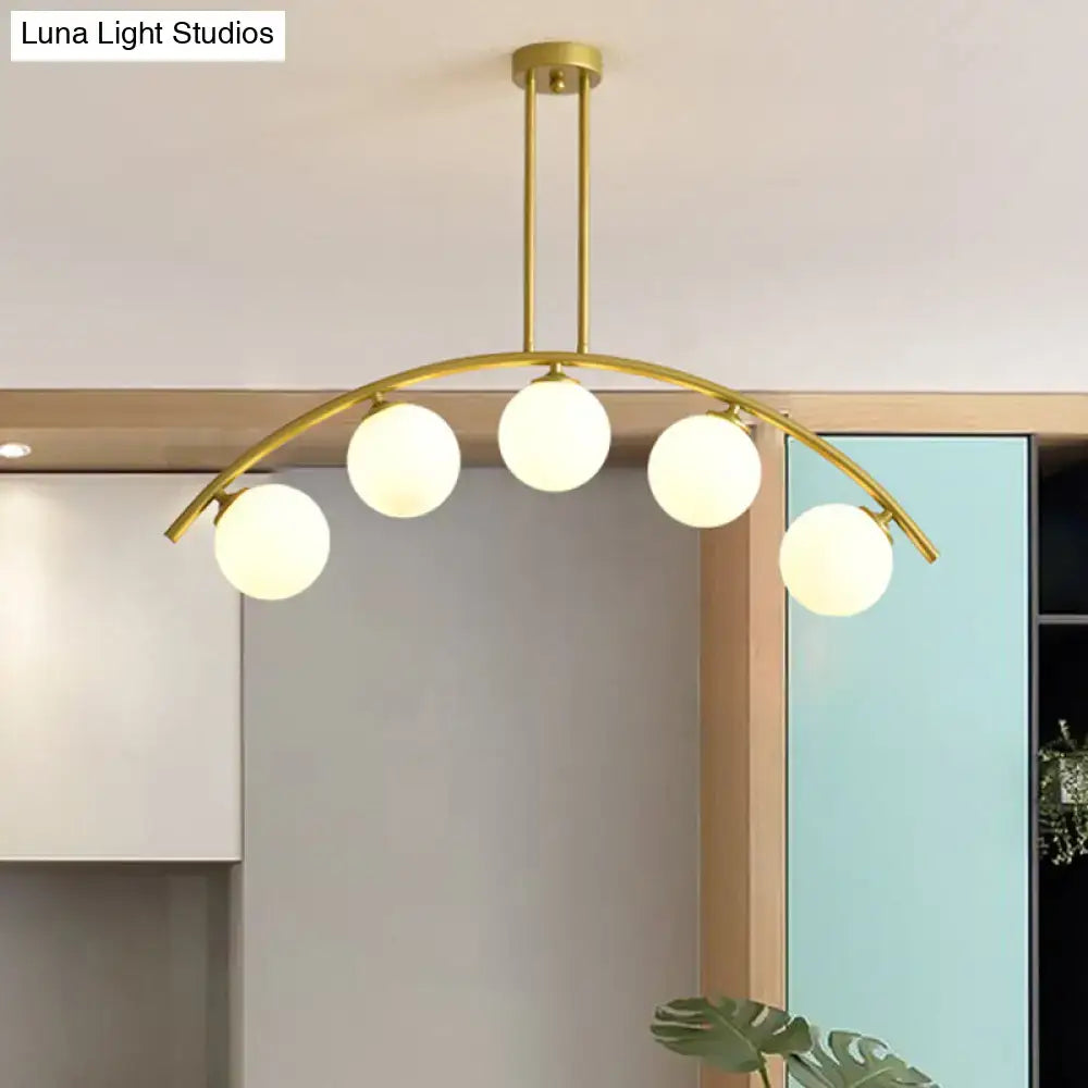 Gold-toned DecorBites island pendant with five frosted glass globes and clear white shade for modern kitchens