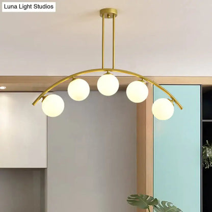 Gold-toned DecorBites island pendant with five frosted glass globes and clear white shade for modern kitchens