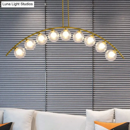 Gold-toned decorbites island pendant with nine glowing spherical glass bulbs and clear white shade for modern kitchens