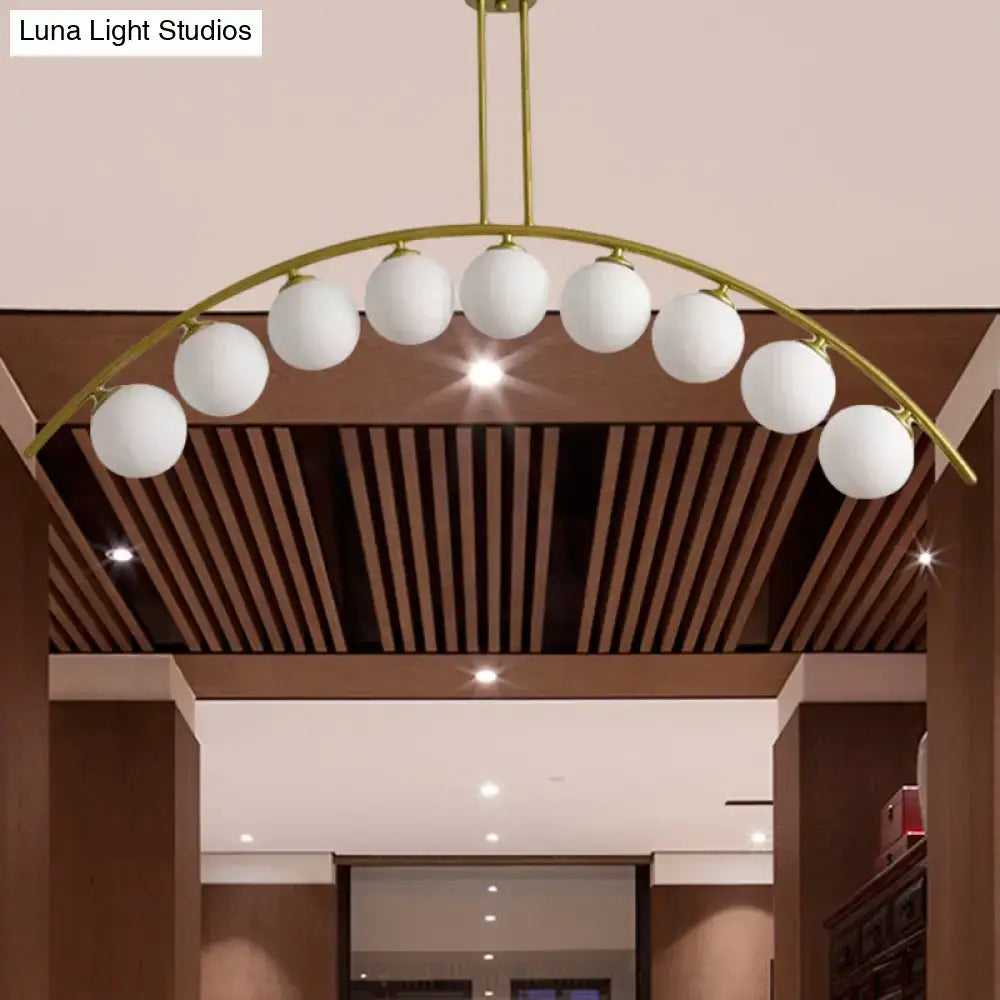 Gold-toned DecorBites island pendant with eight frosted white shade globes featuring a clear white shade design