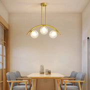 Gold-toned decorbites island pendant with clear white shade and three spherical glass bulbs for modern kitchens
