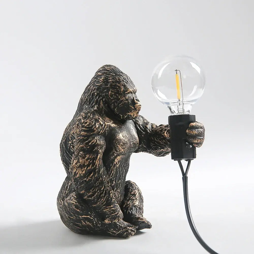 Modern gold king kong resin night light featuring a bronze-finished gorilla figurine holding a clear glass bulb decorbites king kong decor
