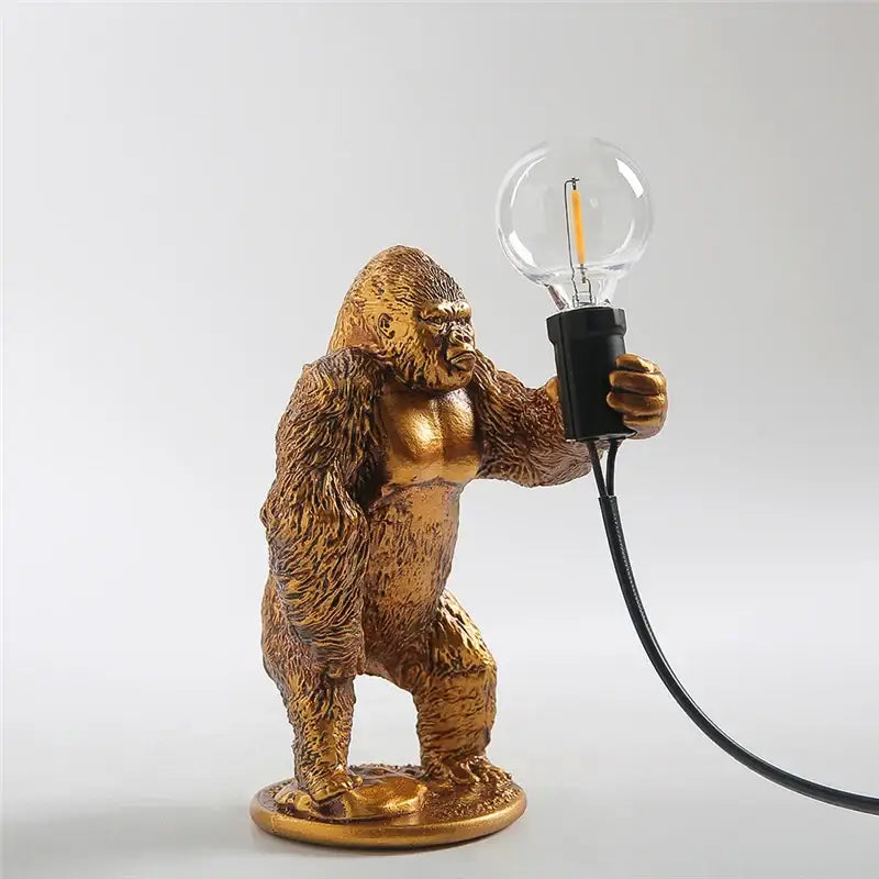 Modern gold king kong resin night light table lamp featuring a golden gorilla figurine holding a clear bulb decorbites king kong
