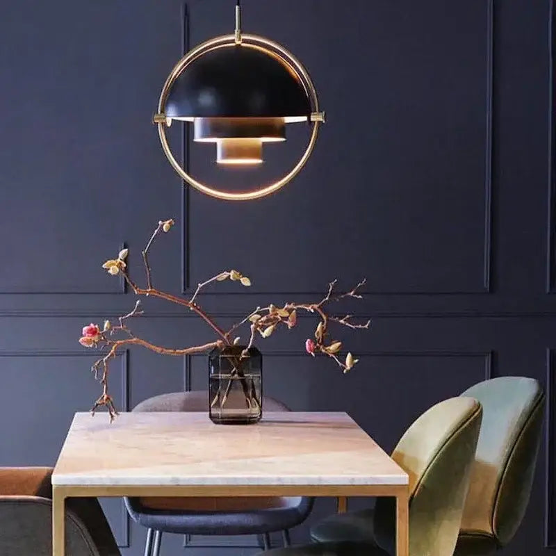 Modern gold layered danish pendant light featuring a black and gold spherical pendant light above a dining table
