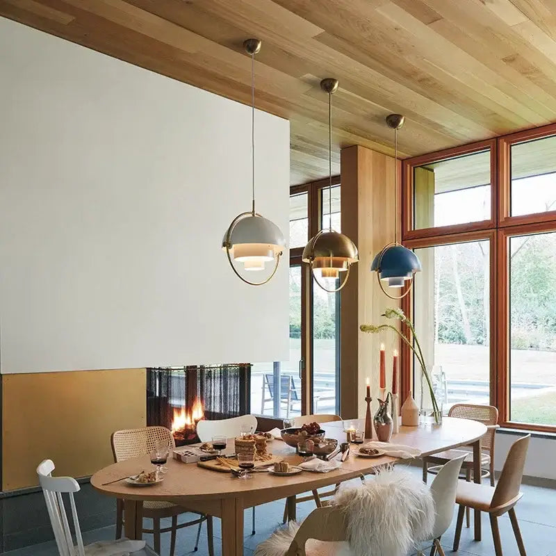 Three modern pendant lights with matte gray brass and navy blue spherical shades in gold layered danish pendant light design