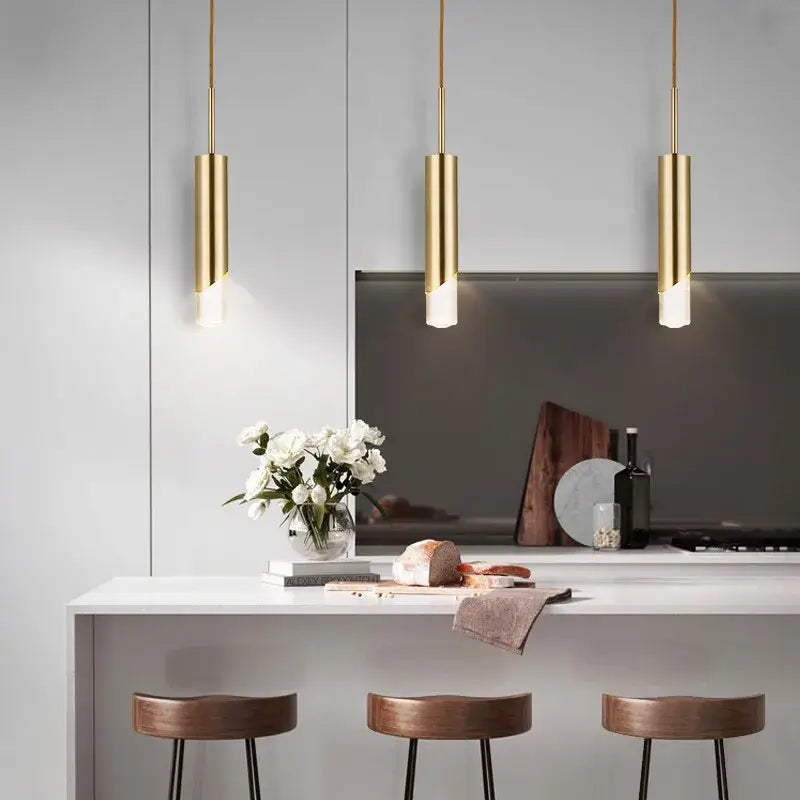 Three sleek cylindrical gold led pendant lights hang above a modern kitchen island decorbites gold led pendant light decor
