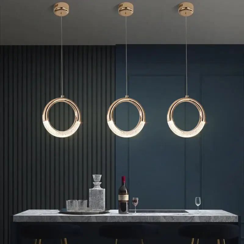 Three modern gold led pendant lights with circular illuminated rings hang above a marble countertop decorbites gold led