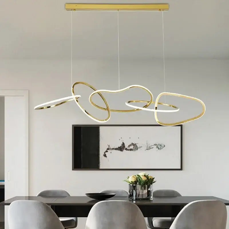 Modern gold led ring chandelier with interconnected abstract rings suspended above dining table for decorbites gold led decor