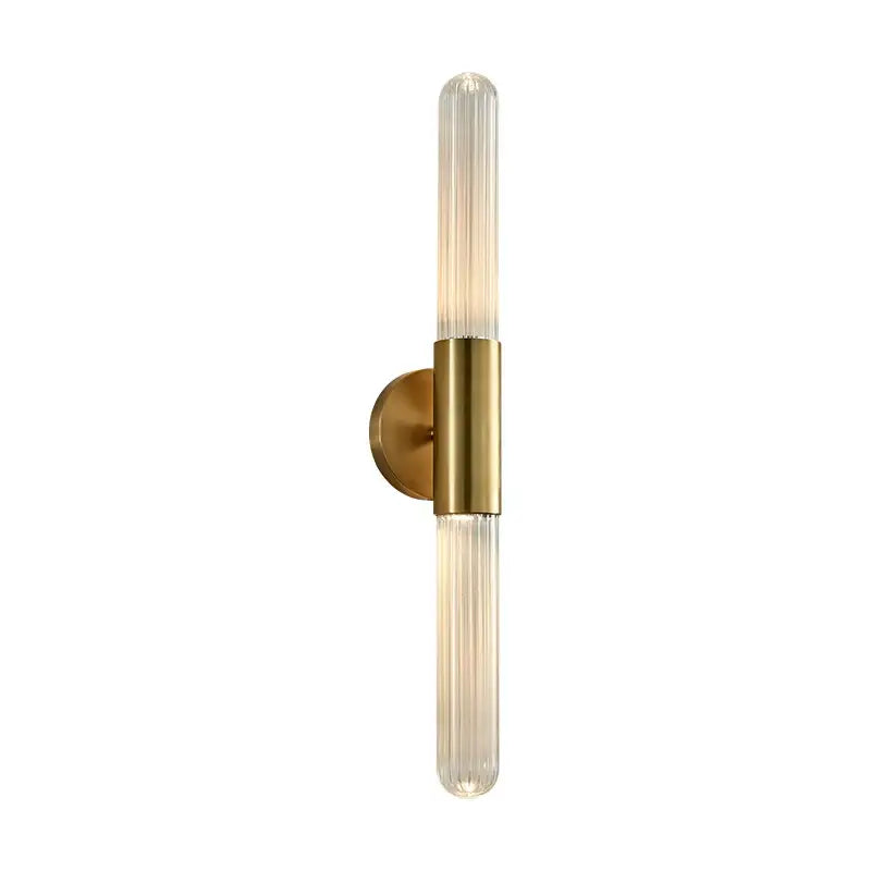 Modern gold led sconce with a sleek brass base and two clear white ribbed glass tubes for bedroom wall lighting