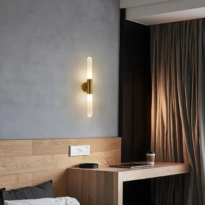 Modern gold led sconce with clear white glass and brass wall mount featuring a frosted glass cylinder for bedroom lighting