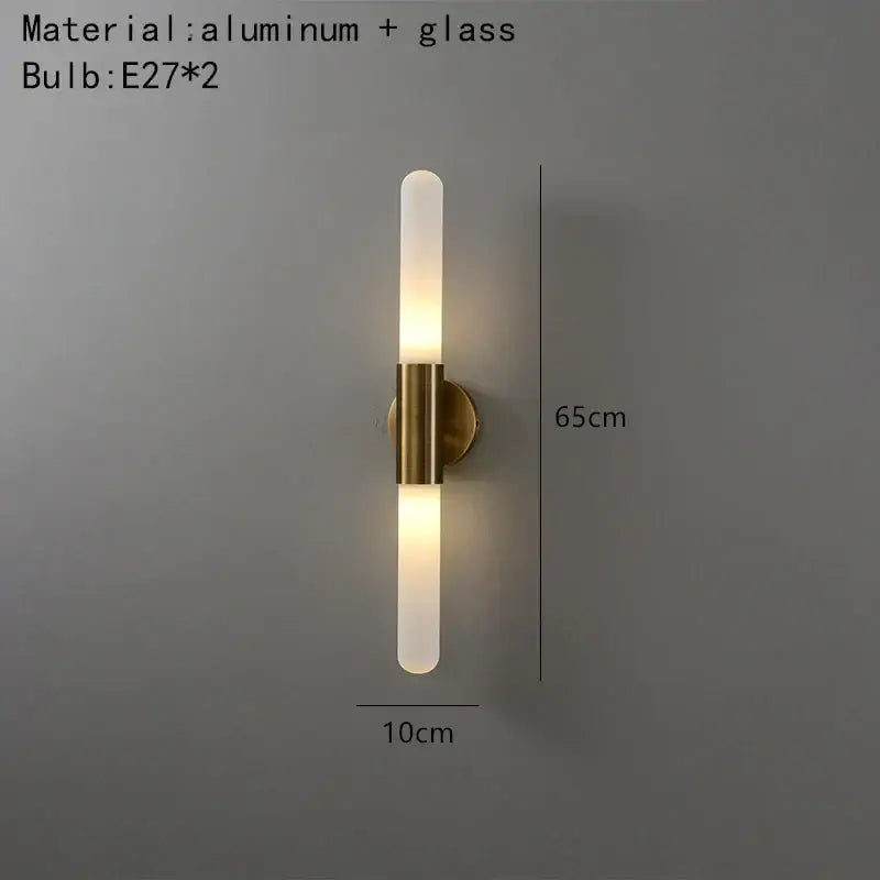 Modern gold led sconce with clear white glass frosted cylindrical shades and brass-finished aluminum mounting base for bedroom wall light